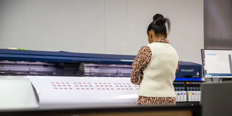 Woman checking large printer output in office.