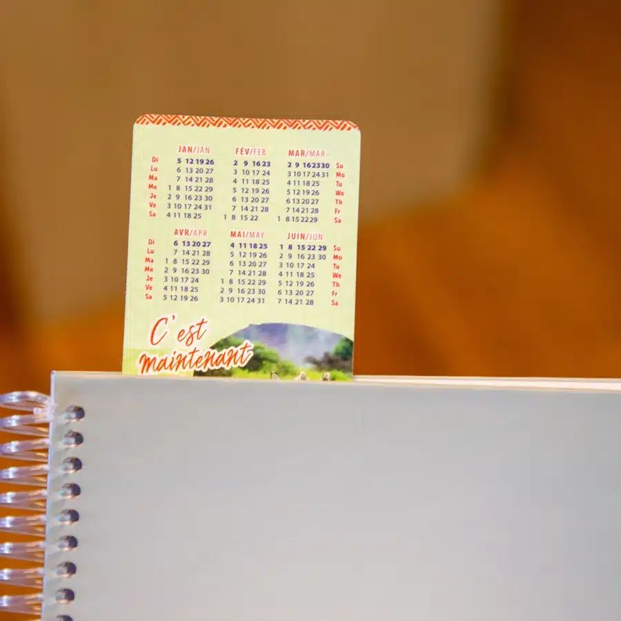 Calendar on spiral notebook, French text 'C'est maintenant'.