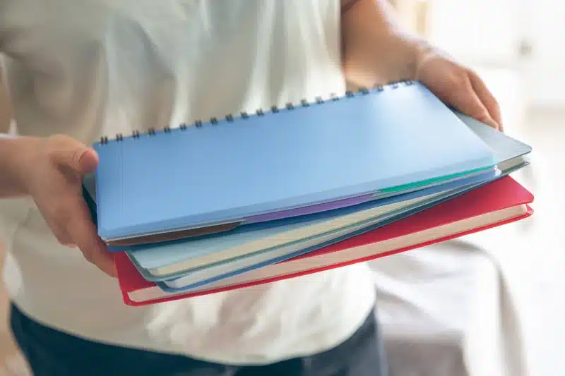 Person holding colorful spiral notebooks.